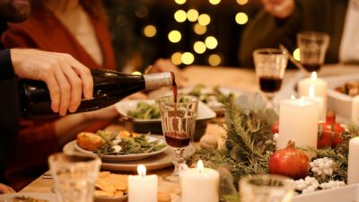 Warm holiday dinner setting with festive decorations, candles, and wine pouring for a joyful celebration.
