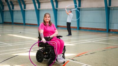 Woman in wheelchair with hula hoop, man in background