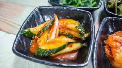 Delicious spicy Korean cucumber salad served in a black bowl, showcasing vibrant colors.
