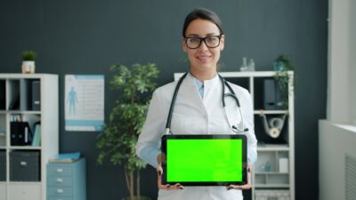 Doctor holding a tablet with a green screen.