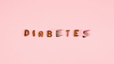 Creative typography of the word 'diabetes' with cookie cutters on a pink background.