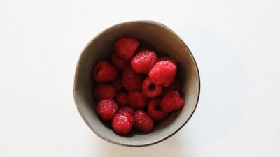 a bowl of raspberries on a white table