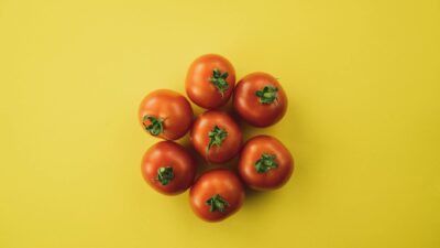 Top view of ripe tomatoes arranged on a vivid yellow surface, emphasizing freshness and nutrition.