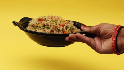 person holding black ceramic bowl with rice