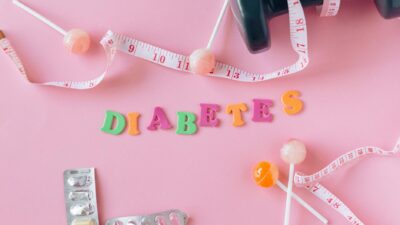 Creative flat lay display of diabetes-related items with a pink backdrop. Ideal for health-related concepts.
