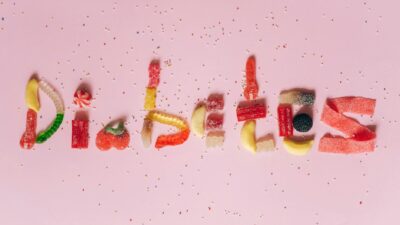 Candies shaped to spell diabetes on a pink background, highlighting sugar intake
