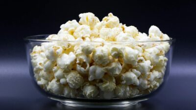 Close-up of freshly popped popcorn in a clear glass bowl, perfect snack idea.