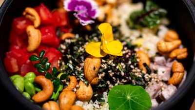 A colorful bowl of rice with cashews and vegetables.