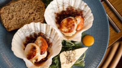 Seared scallops are served in shells with bread.