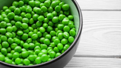 a bowl filled with green peas on top of a white table
