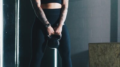 a woman with tattoos holding a kettle in a gym