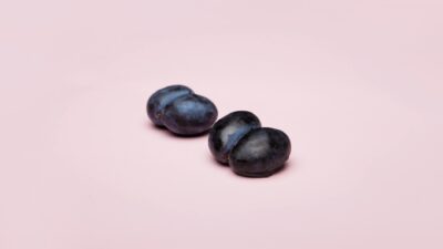 Artistic composition of grapes resembling shapes on light pink background.