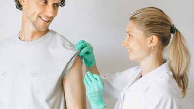 A nurse administering a vaccination shot to a smiling patient indoors.