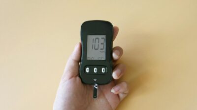 Hand holding a blood glucose meter displaying glucose levels, highlighting diabetes monitoring.