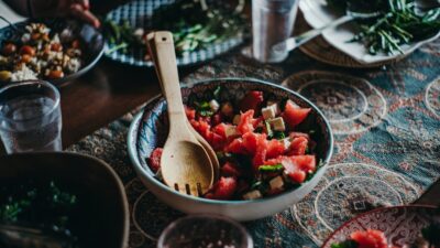 a bowl of watermelon salad with a wooden spoon