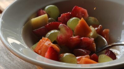 A bowl of fresh fruit salad with grapes and strawberries