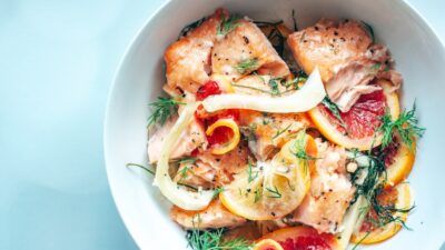 a white bowl filled with meat and oranges