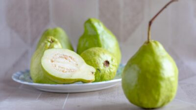 Fresh green guavas on a plate, showcasing their vibrant color and texture.