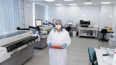 A scientist in protective gear holding test samples in a modern laboratory setting.