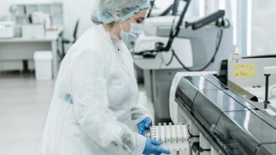 Laboratory scientist in protective gear working with medical samples.