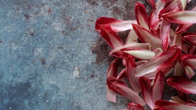 A vibrant display of red chicory leaves on a textured, rustic surface, perfect for food styling and backgrounds.