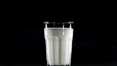 A glass of fresh milk against a black background, emphasizing simplicity and nutrition.