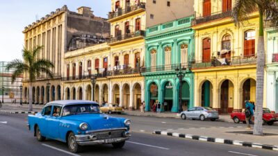 Explore Havana's vibrant city streets with a classic car cruising past colorful colonial facades.