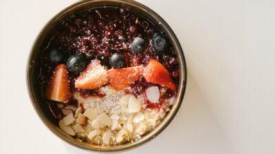 A vibrant oatmeal breakfast bowl with berries and almonds on a white surface.
