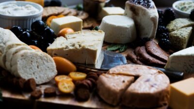 a wooden cutting board topped with lots of different types of cheese