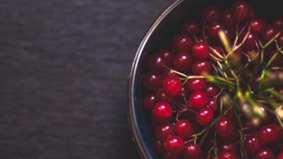 a metal bowl filled with red berries on top of a wooden table