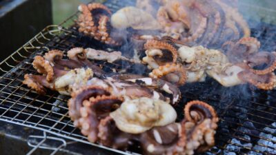 Fresh octopus sizzling on an outdoor grill, showcasing traditional seafood barbecue techniques.