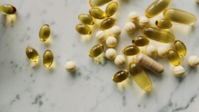 Variety of supplements and capsules scattered on a marble surface, suitable for healthcare themes.