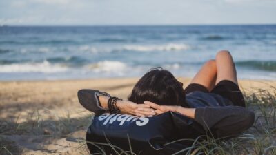 woman lying on grass front of sea at daytime